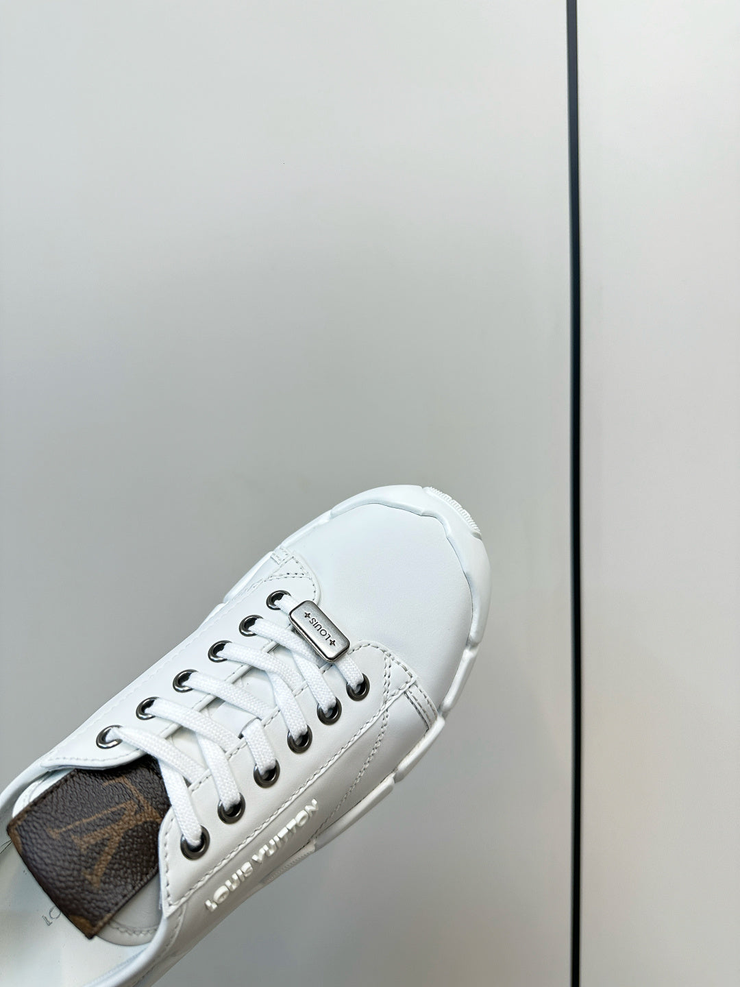 White sneaker side view with dark interior lining and lace-up eyelets
