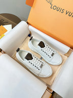 White lace-up sneakers resting in a box, with dark heel tabs and sole details
