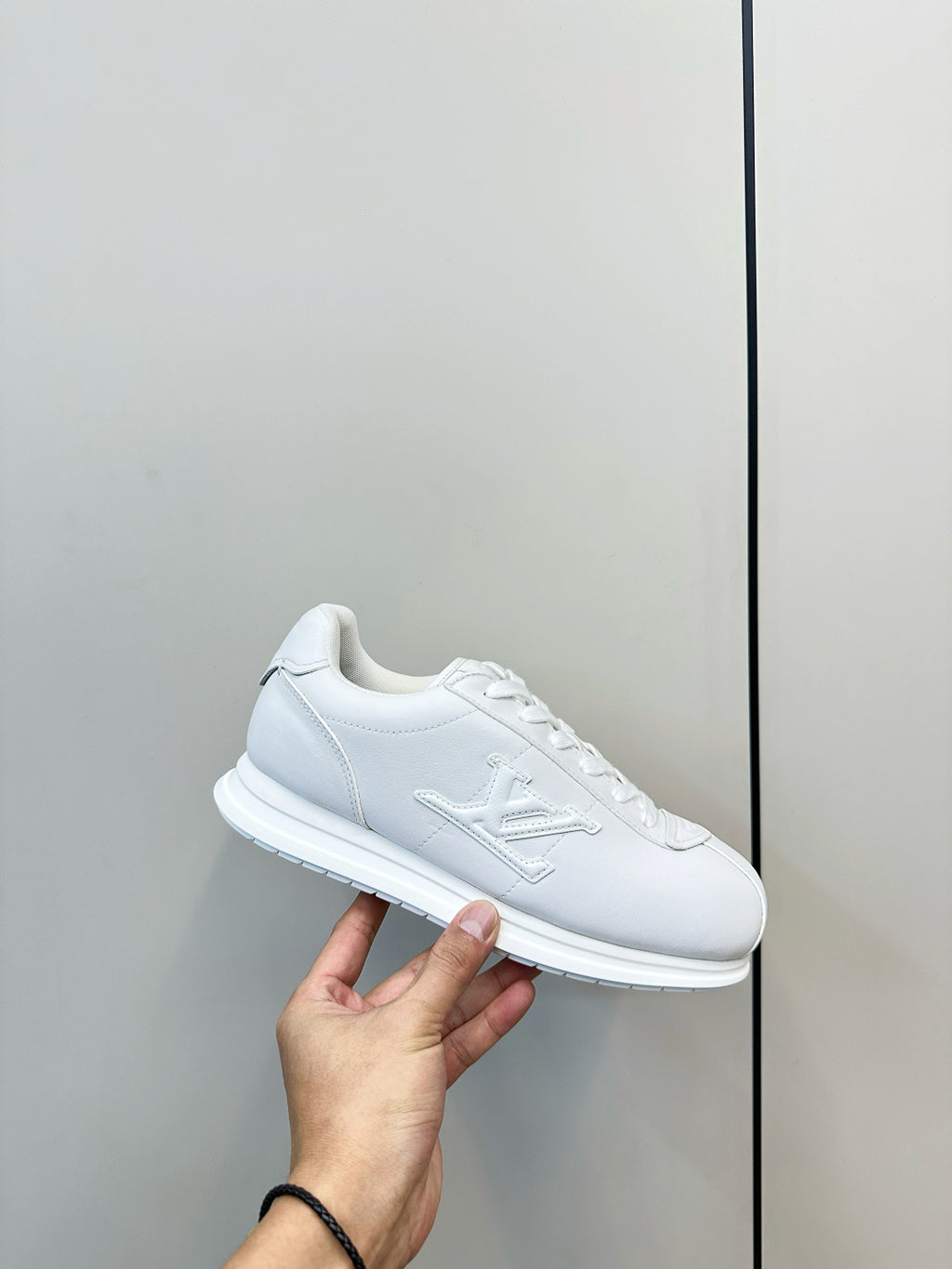 Louis Vuitton white lace-up sneaker close-up with hand holding shoe