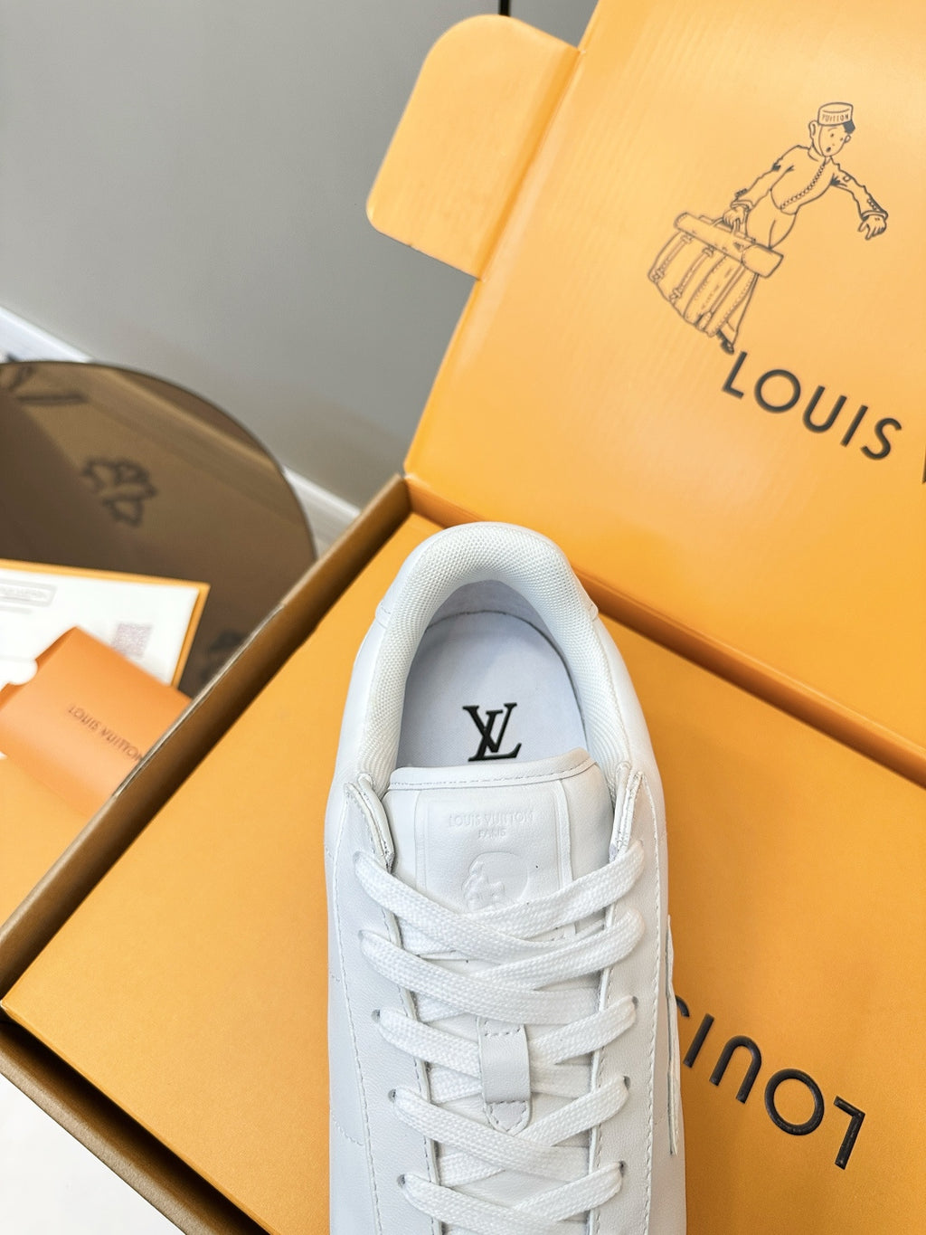 Louis Vuitton white sneaker close-up, logo on tongue and lace-up front