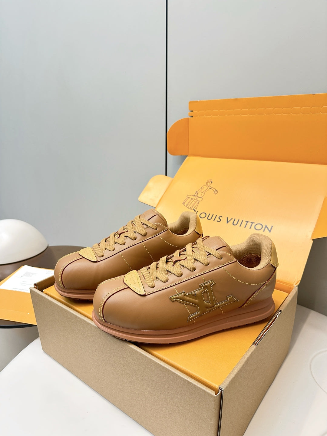 Tan lace-up low-top sneakers with LV side logo, seated on shoe box