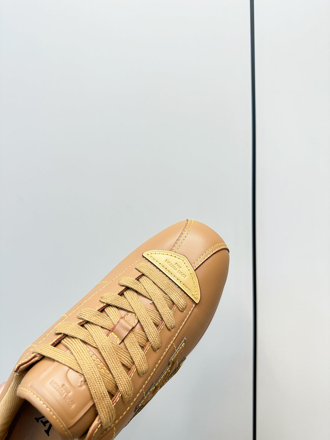 Close-up of tan lace-up sneaker upper with LV logo and textured sole