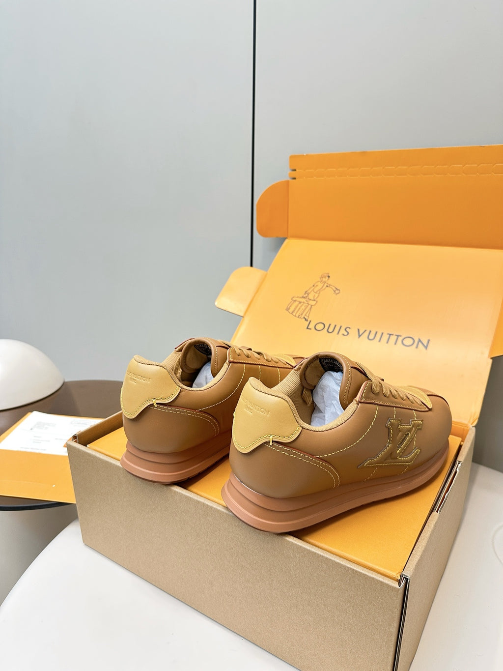 Tan lace-up low-top sneakers with LV logo on sides, heels shown
