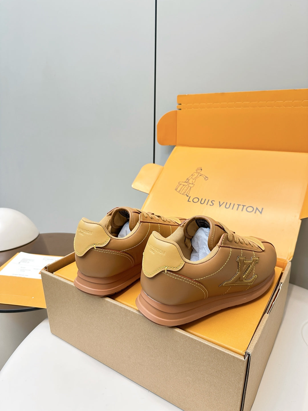 Tan lace-up low-top sneakers with LV logo on sides, heels shown