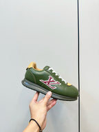 Green low-top sneaker held in hand, white laces and red LV logo