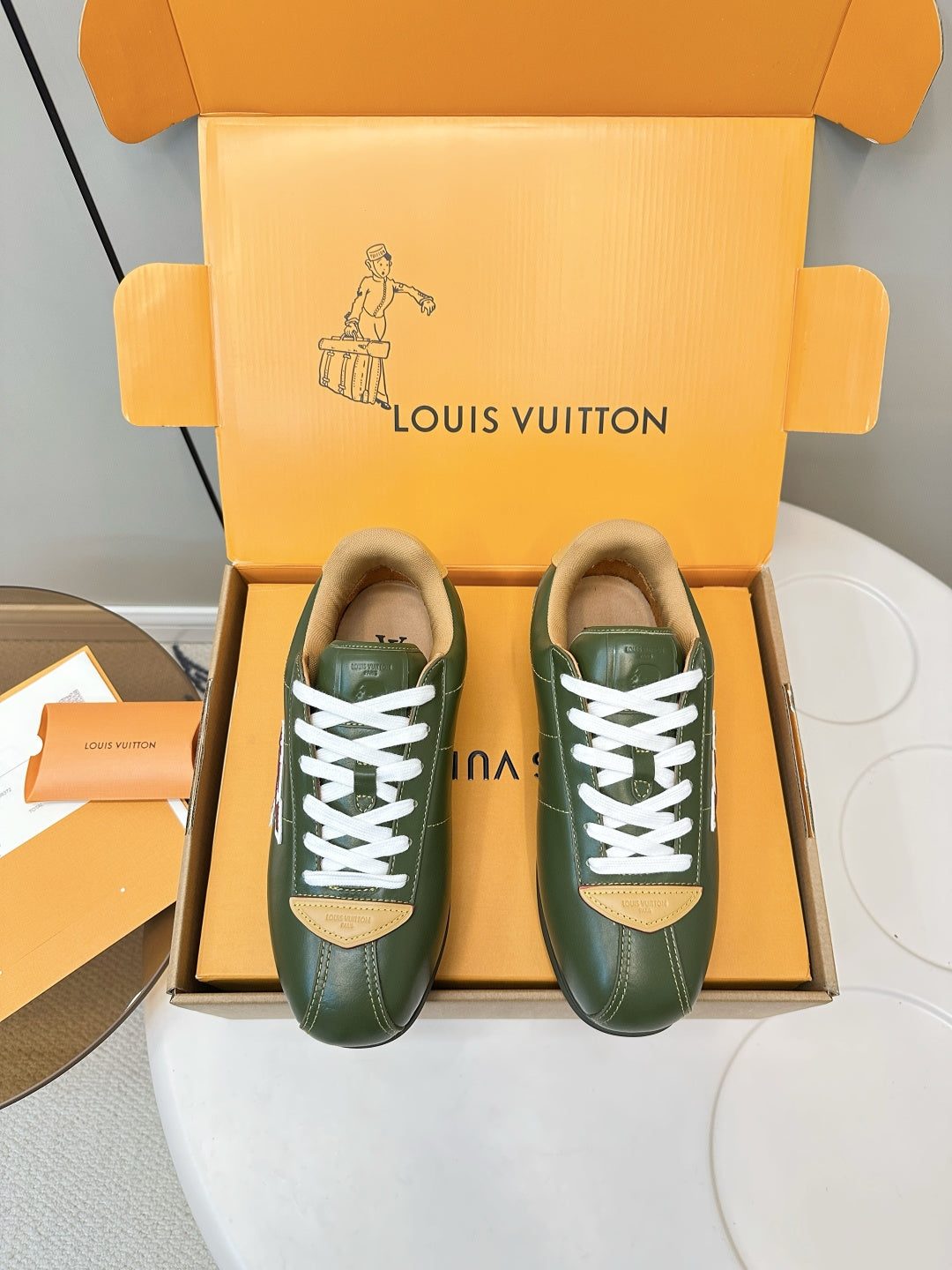 Green low-top sneakers with white laces and LV logo, in orange gift box