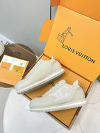 White leather sneakers on box, front pair with tan heel panels and embossed side logo