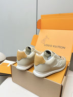 Pair of white leather sneakers with tan heel patches and white rubber sole, angled view