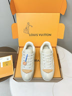White leather sneakers with tan heel panels and white laces, viewed from front in box
