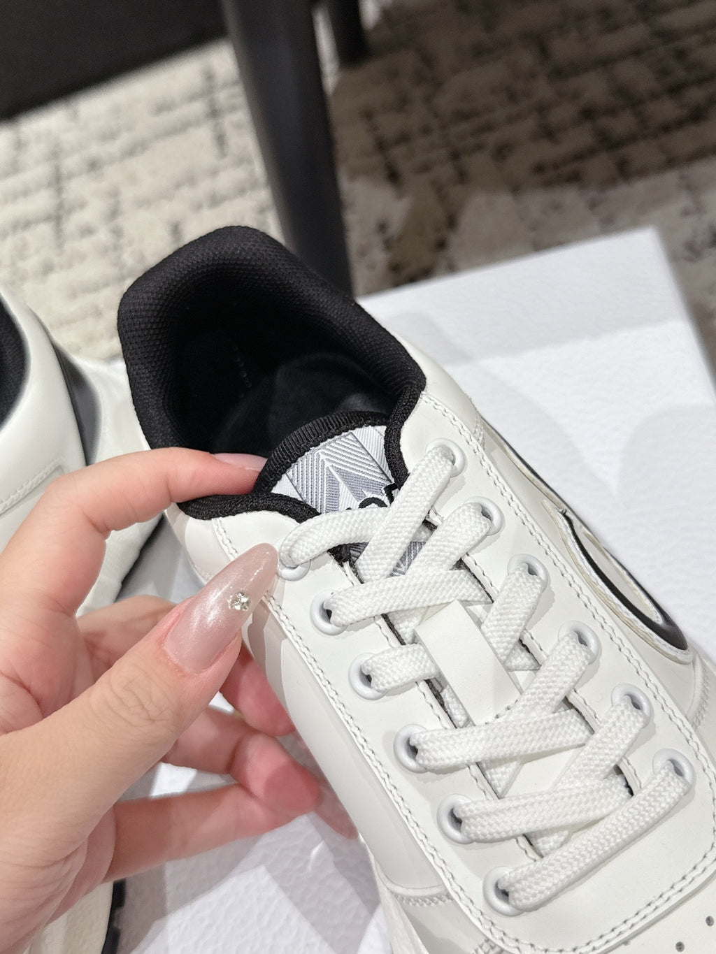 White sneaker close-up showing lace-up, stitching, and perforated toe
