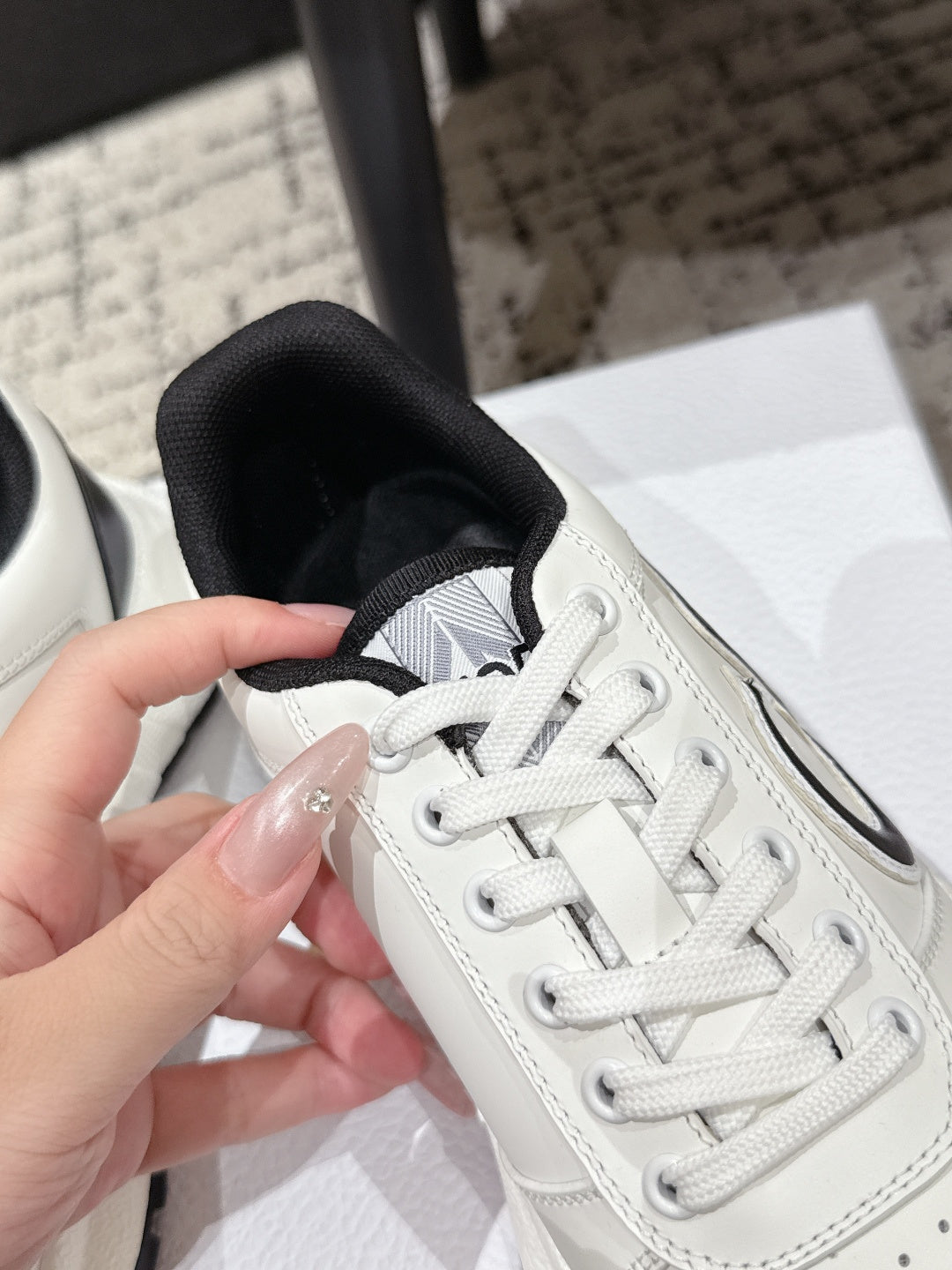 White sneaker close-up showing lace-up, stitching, and perforated toe