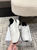 White lace-up sneakers with black collar trim and side logo; hand holding
