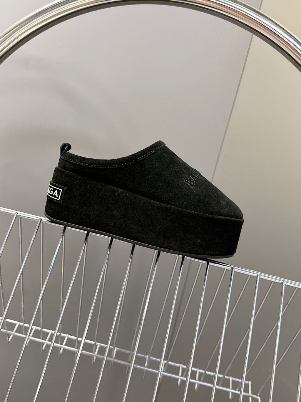 Balenciaga black suede slip-on sandals on display rack, side profile