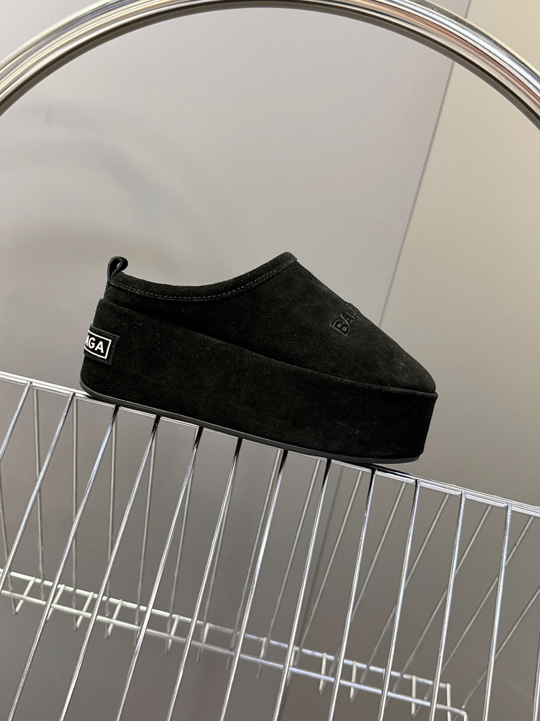 Balenciaga black suede slip-on sandals on display rack, side profile
