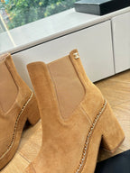 Chanel suede ankle boots close-up: tan upper, chain trim, logo patch on cuff