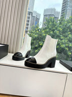 White ankle boots with black toe caps, contrast stitching, and chunky block heels