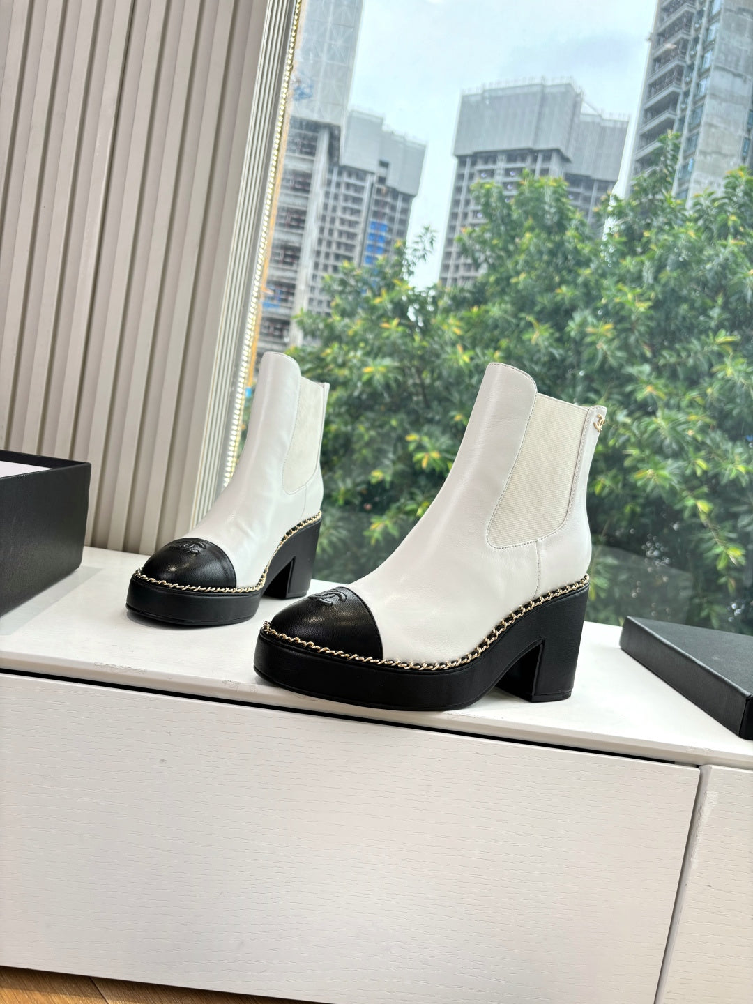 White ankle boots with black toe caps, contrast stitching, and chunky block heels