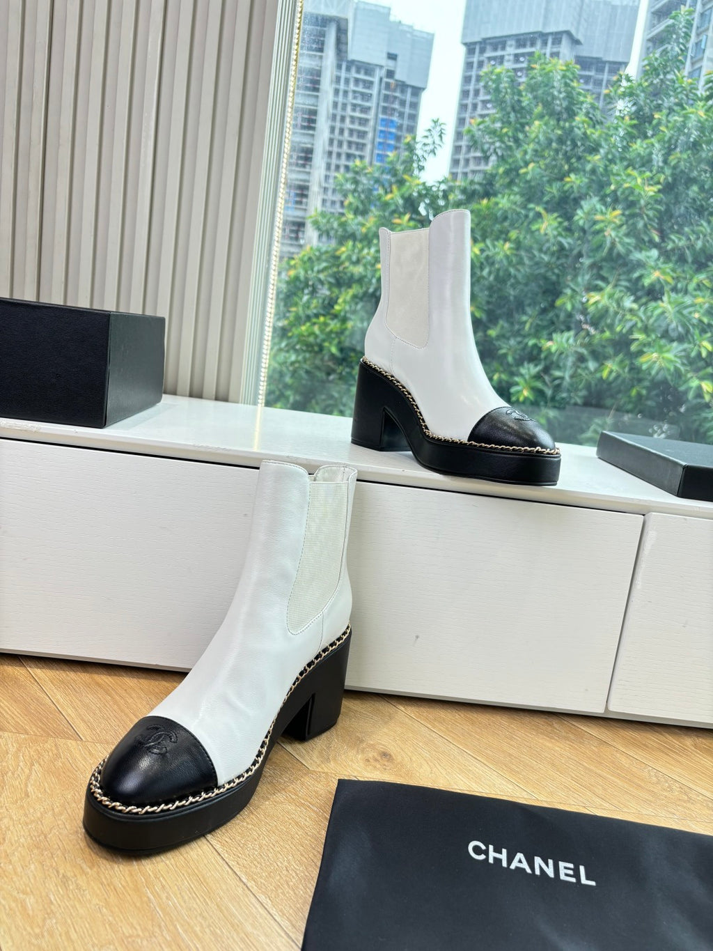 White ankle boots with black toe cap and heel, contrast stitching, and Chelsea fit