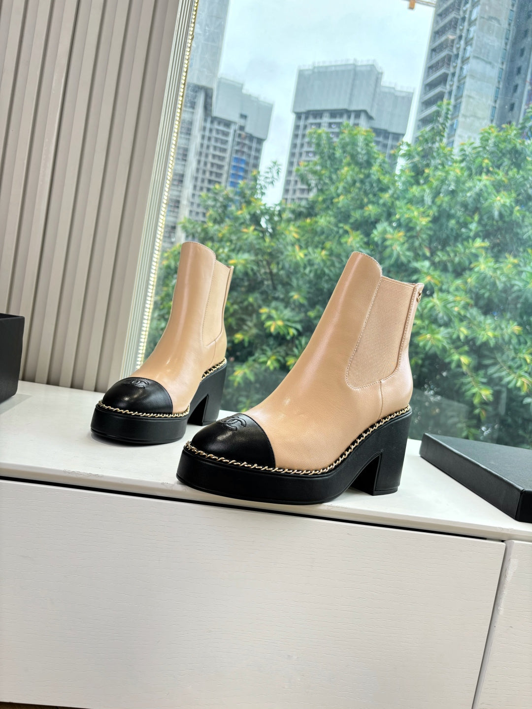 Beige Chelsea-style ankle boots with black toe cap and thick black heel