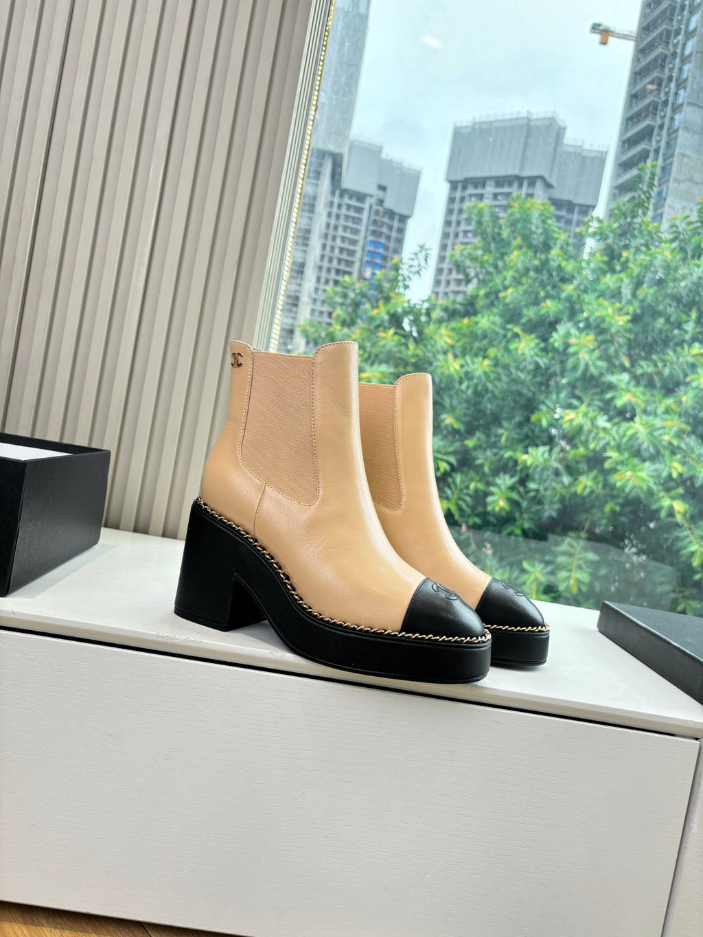 Beige ankle boots with elastic side panels, black sole trim, and block heel