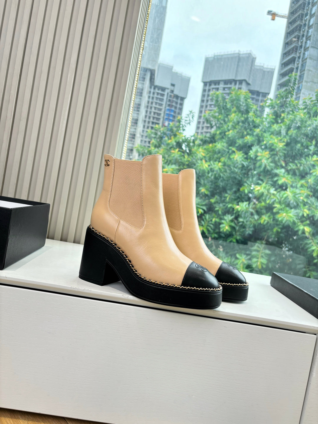Beige ankle boots with elastic side panels, black sole trim, and block heel