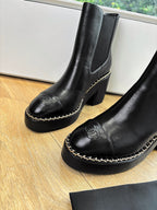 Black ankle boots with thick sole, curved toe, and contrast-stitched trim