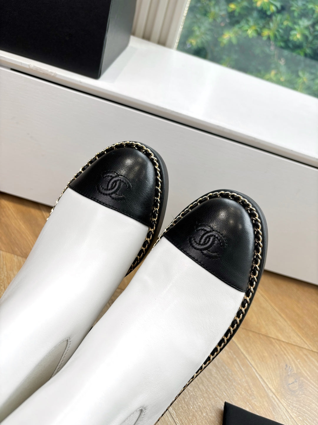 Close-up of black and white Chelsea boots with Chanel logo on toe caps