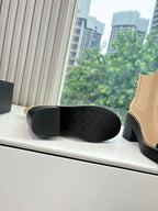 Black outsole and heel view of beige and black ankle boots