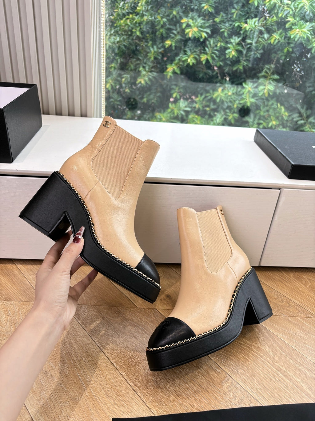 Beige ankle boots with elastic gore and black heel; hand holding one boot