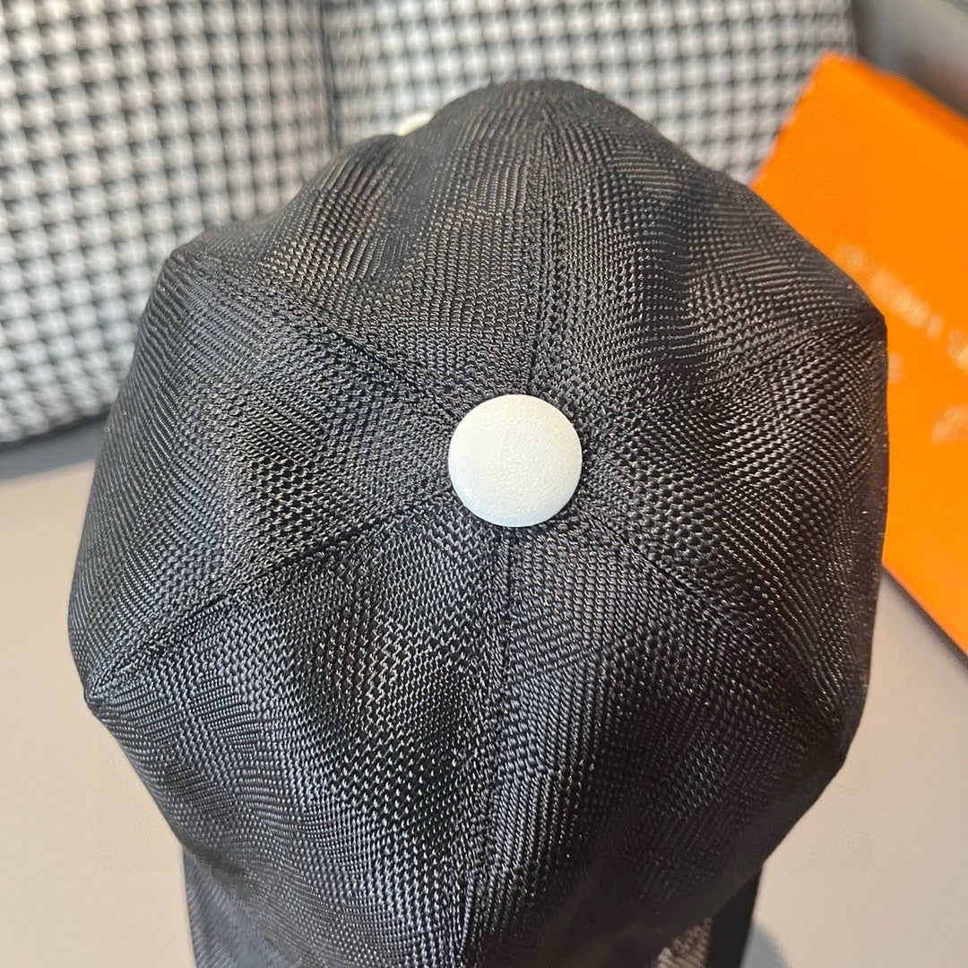 Louis Vuitton dark cap with white top button and stitched crown.