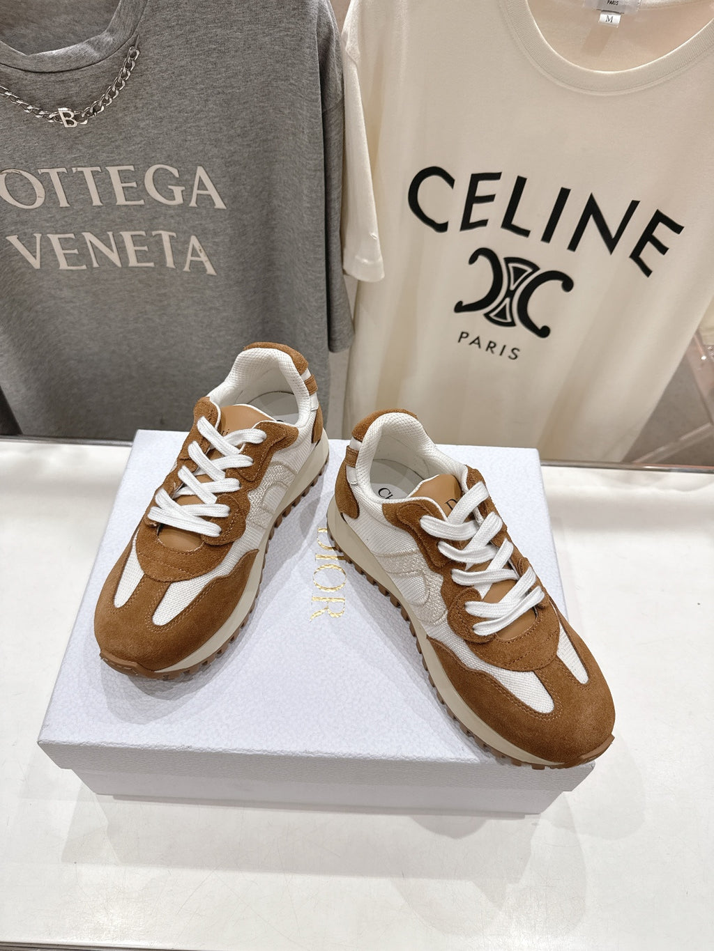 Brown and white low-top sneakers with white laces, angled on a display box