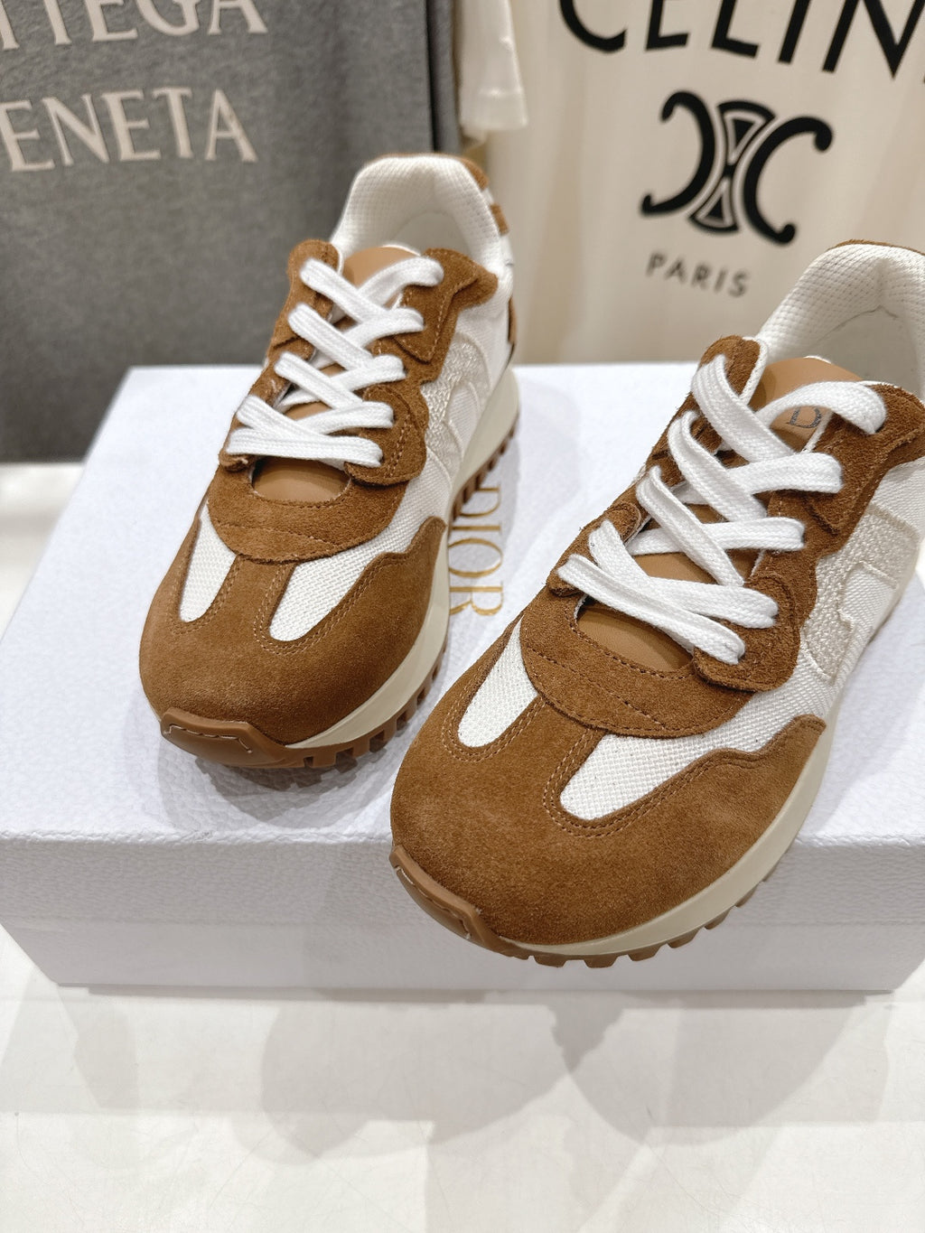 Brown and white sneakers with white laces, two shoes on a display box