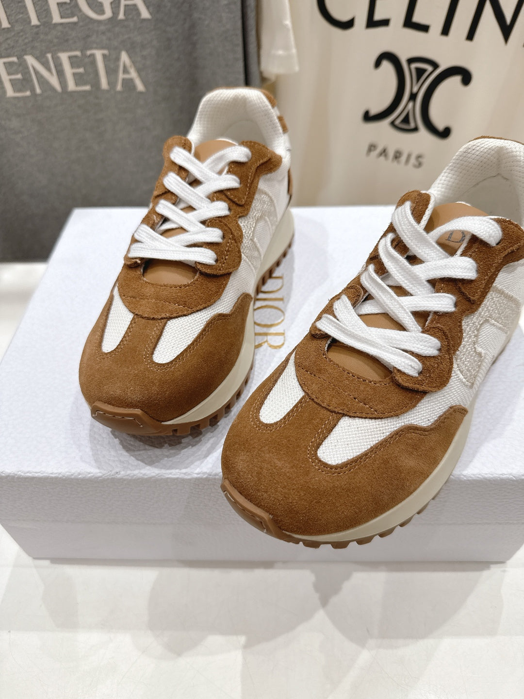 Brown and white sneakers with white laces, two shoes on a display box