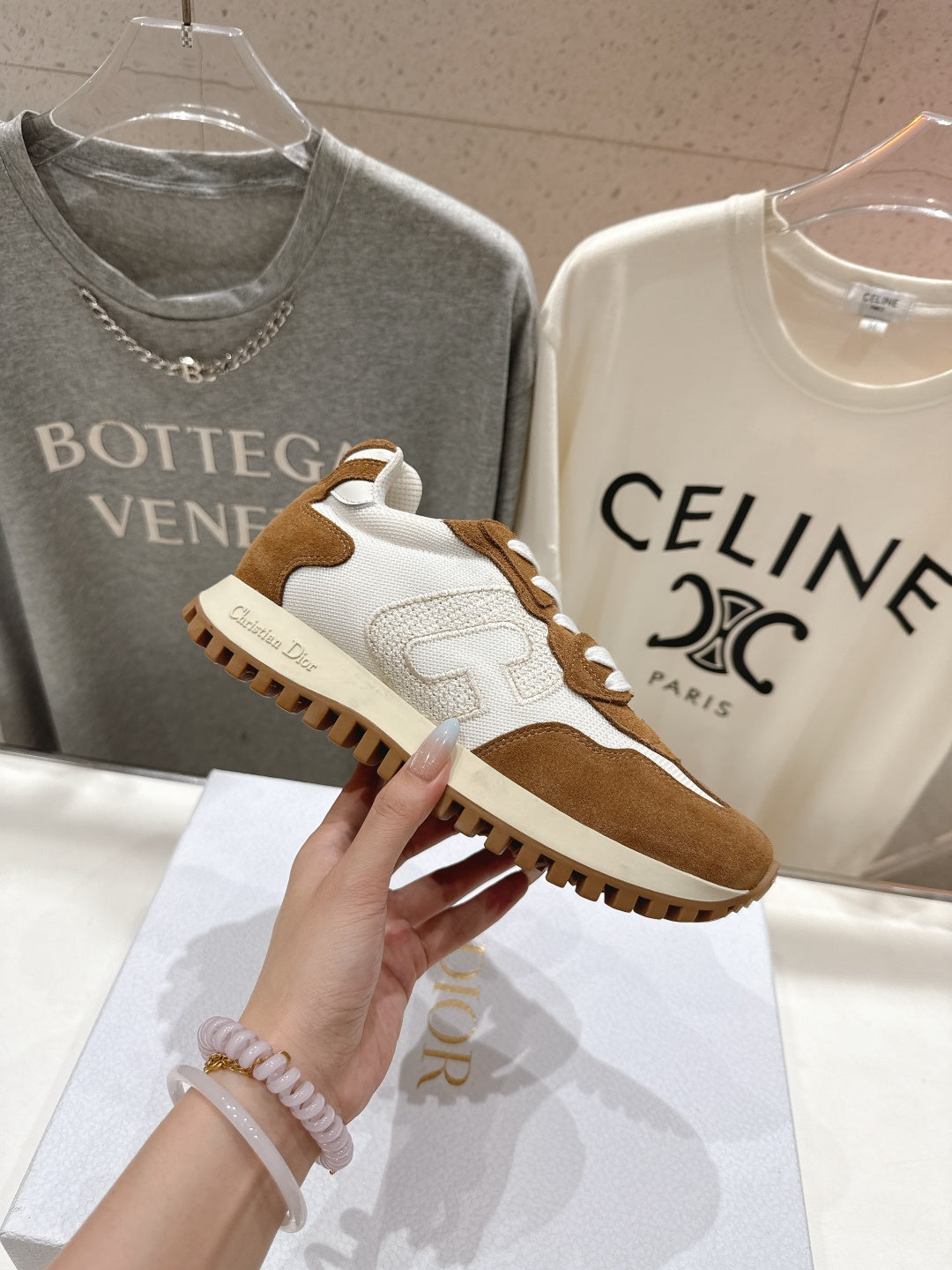 Brown and white sneakers with white laces, side view held in a hand
