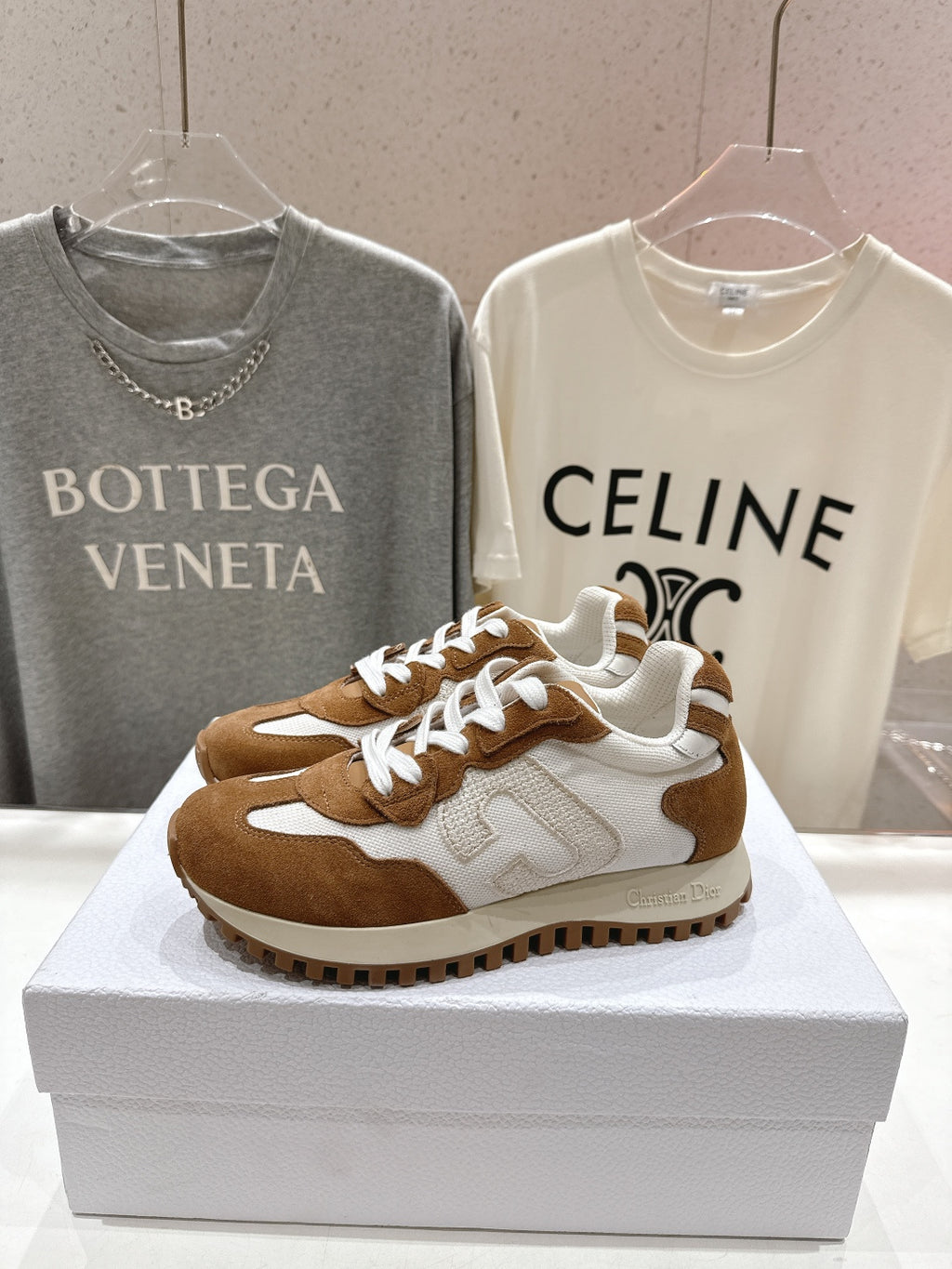 Brown and white sneakers with white laces, front view on a display box