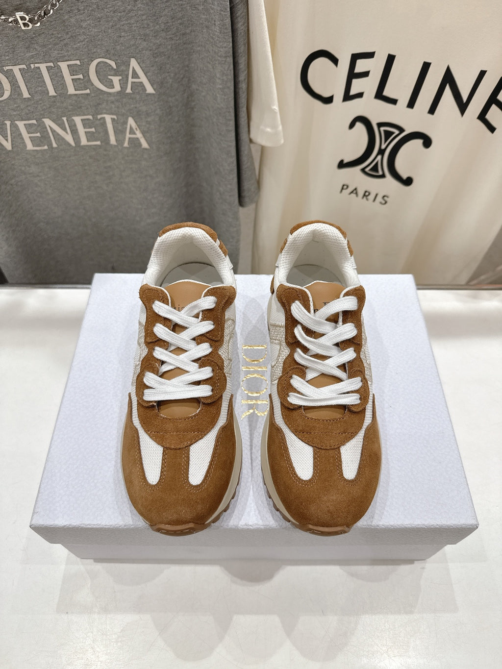 Brown and white sneakers with white laces, side-by-side on a display box