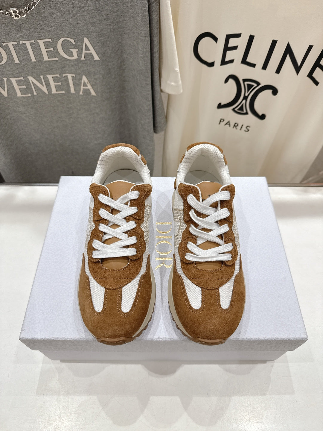 Brown and white sneakers with white laces, side-by-side on a display box