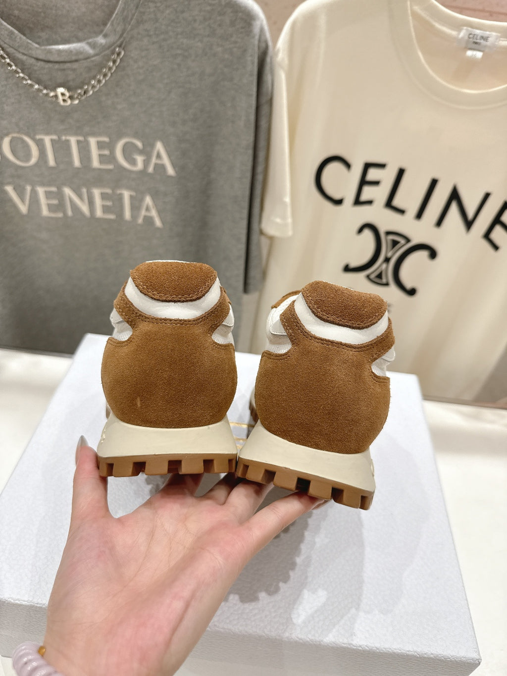 Brown and white sneakers showing textured heel, held above a display box