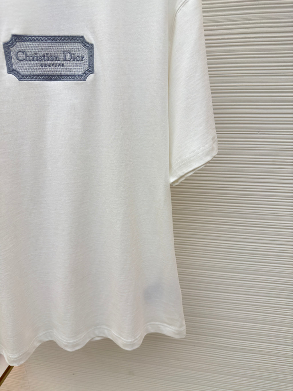 White short-sleeve T-shirt showing lower hem and Christian Dior logo patch