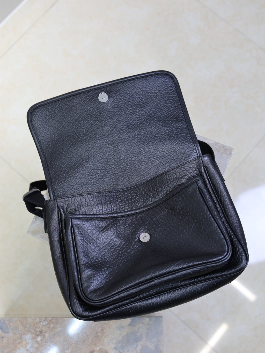 Black textured-leather crossbody bag with front flap and snap button pocket