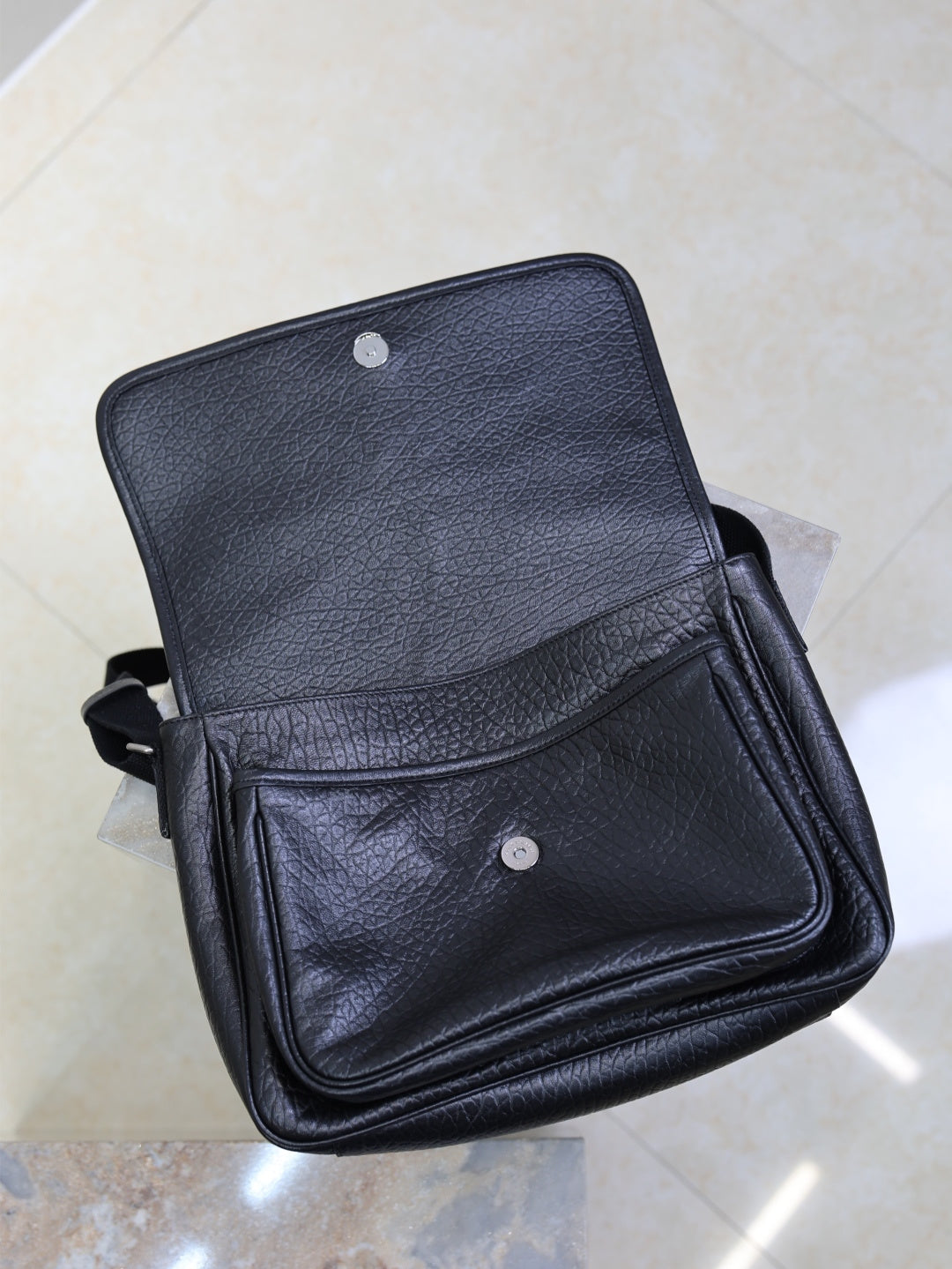 Black textured-leather crossbody bag with front flap and snap button pocket