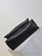 Black textured-leather crossbody bag side view with structured base and seams