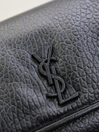 Close-up of black textured-leather flap with YSL logo metal emblem