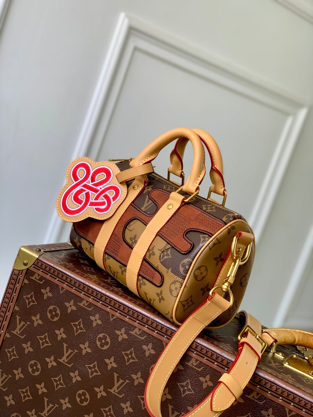 Designer monogram handbag with tan handles, gold hardware, and top flap