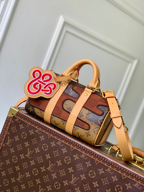 Designer monogram handbag with tan leather straps and front patch detail