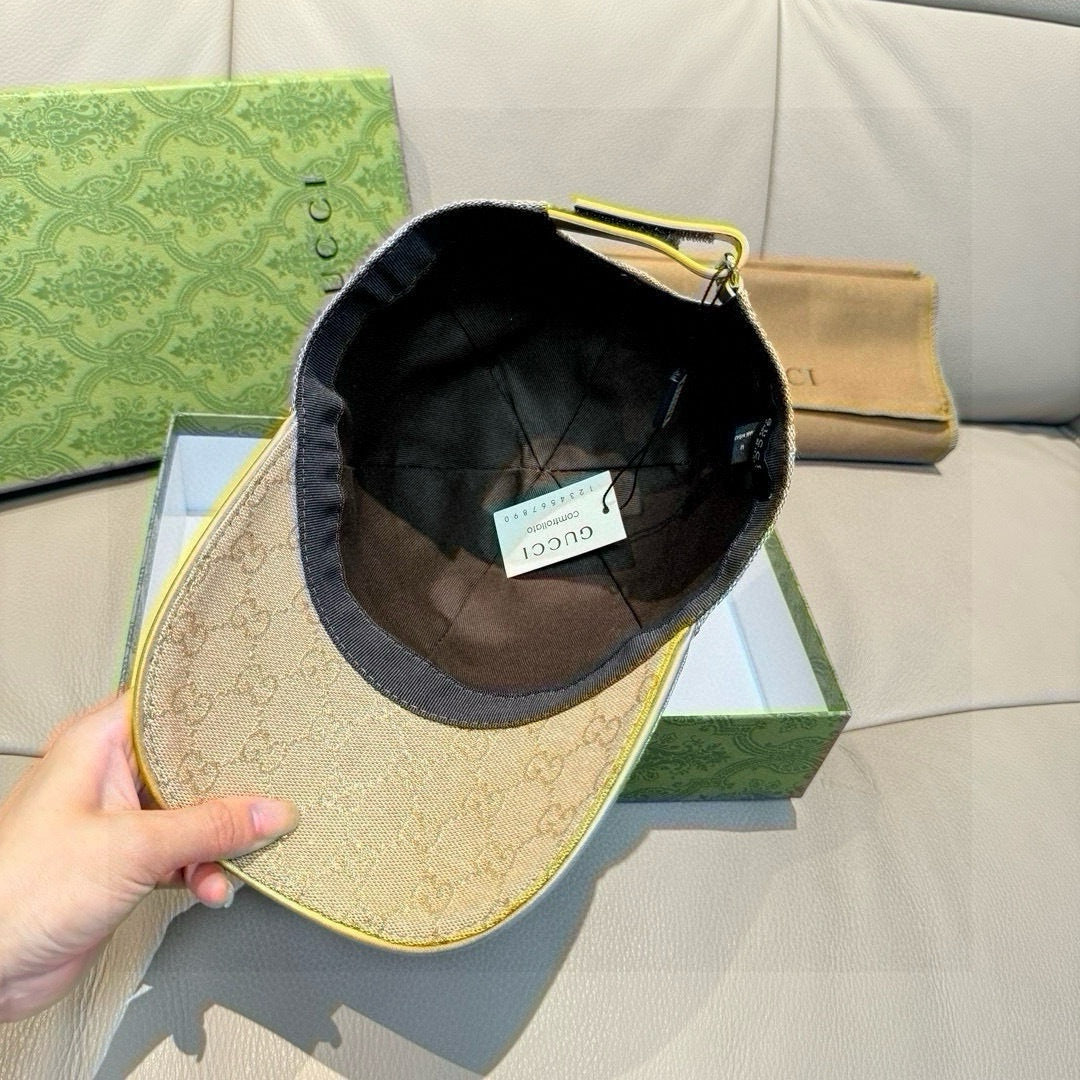 Beige GG monogram baseball cap held up by hand, showing dark interior lining.
