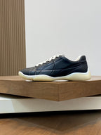 Unisex low-top sneakers, dark navy upper with white laces and cream rubber sole.