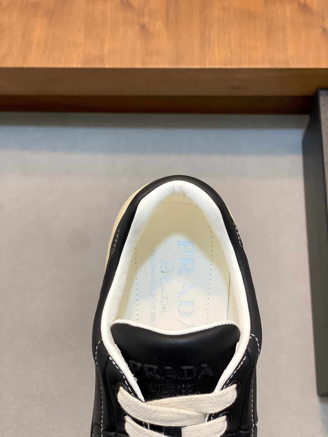 Unisex low-top sneakers with PRADA logo on tongue, black upper and white laces.