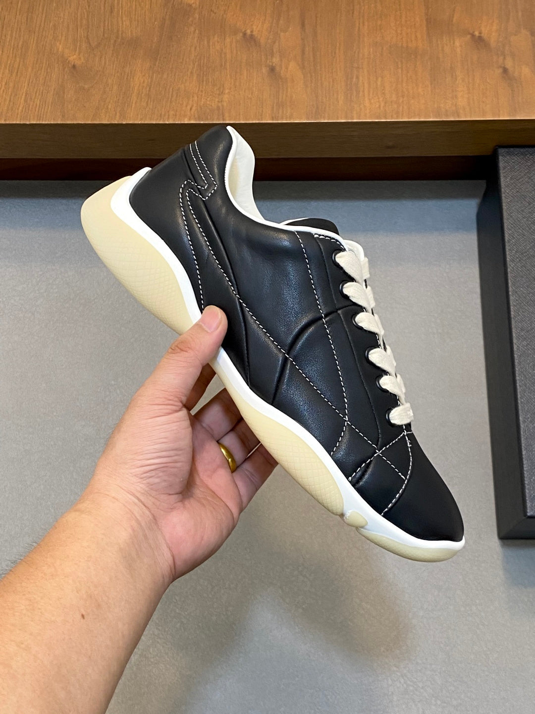 Unisex low-top sneakers, black upper with white laces, stitched details, cream sole.