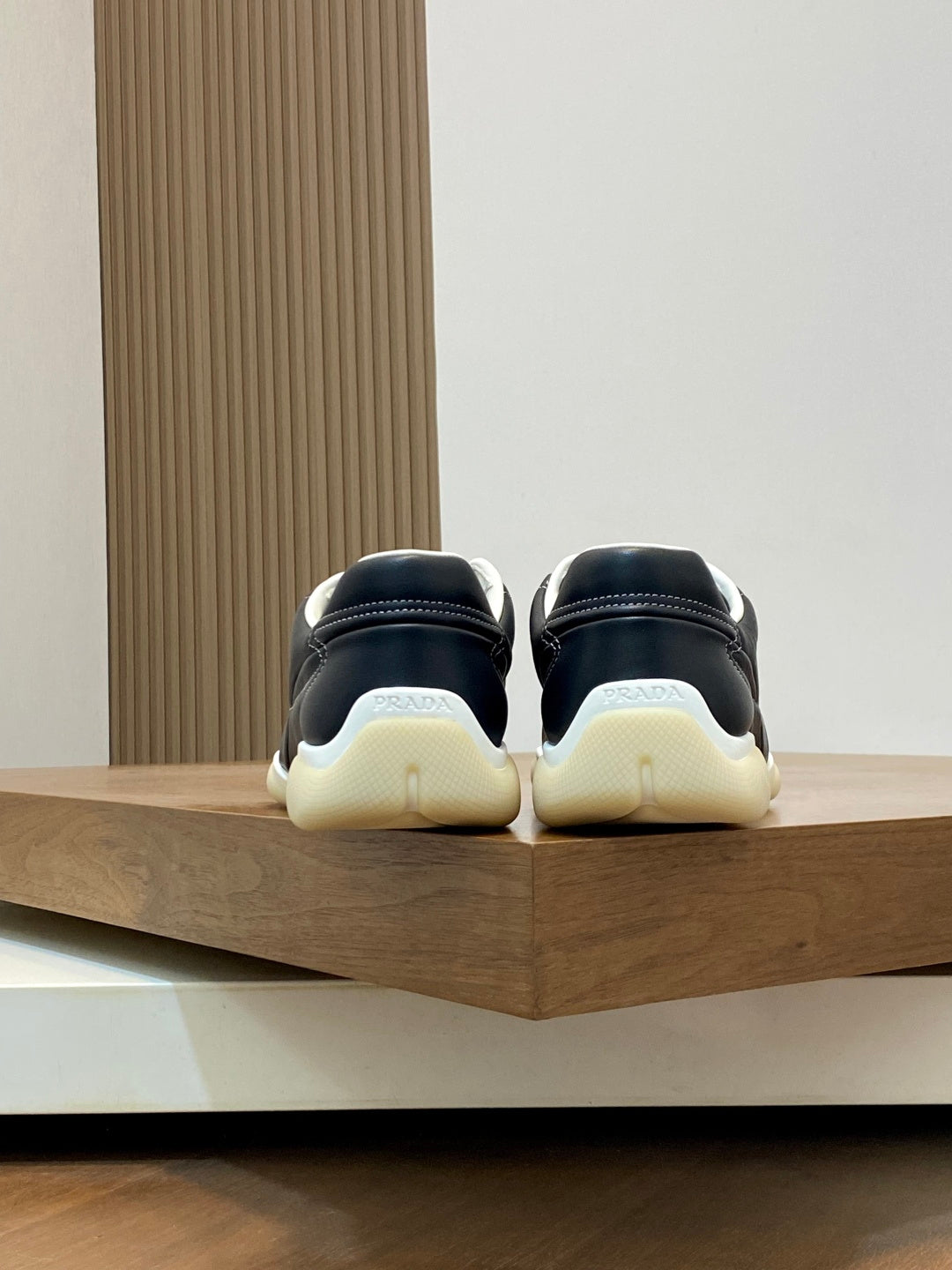 Unisex sneakers rear view, black uppers with cream soles and white lining details.